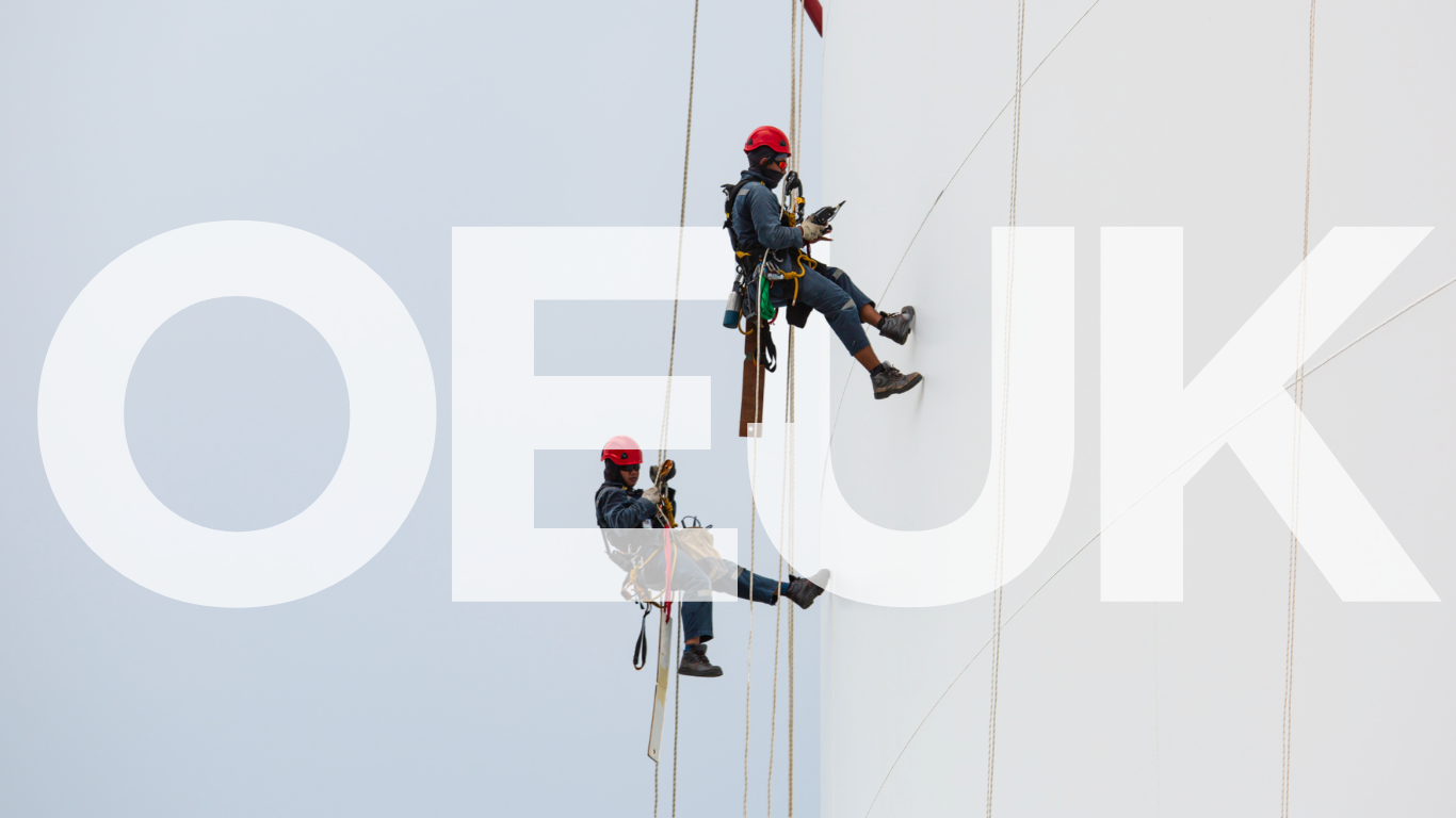 Two workers in safety gear and helmets are rappelling down the side of a large white wind turbine.